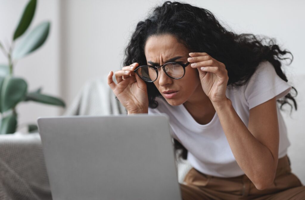 A person adjusting their glasses to squint at a computer screen, wondering why their eyesight keeps getting worse.