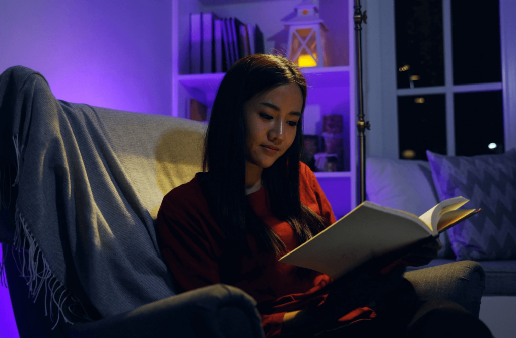 A university student reads a novel in a poorly-lit dorm room.